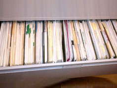 A lateral file cabinet drawer open to reveal papers