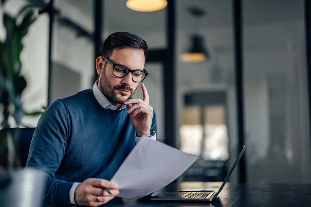 A serious businessman at his desk reviewing accounts payable services by a third party vendor.