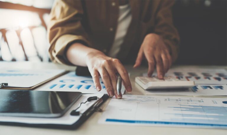 Close up of business woman or accountant working on calculator to calculate business data, accountancy document and laptop computer at office, business concept