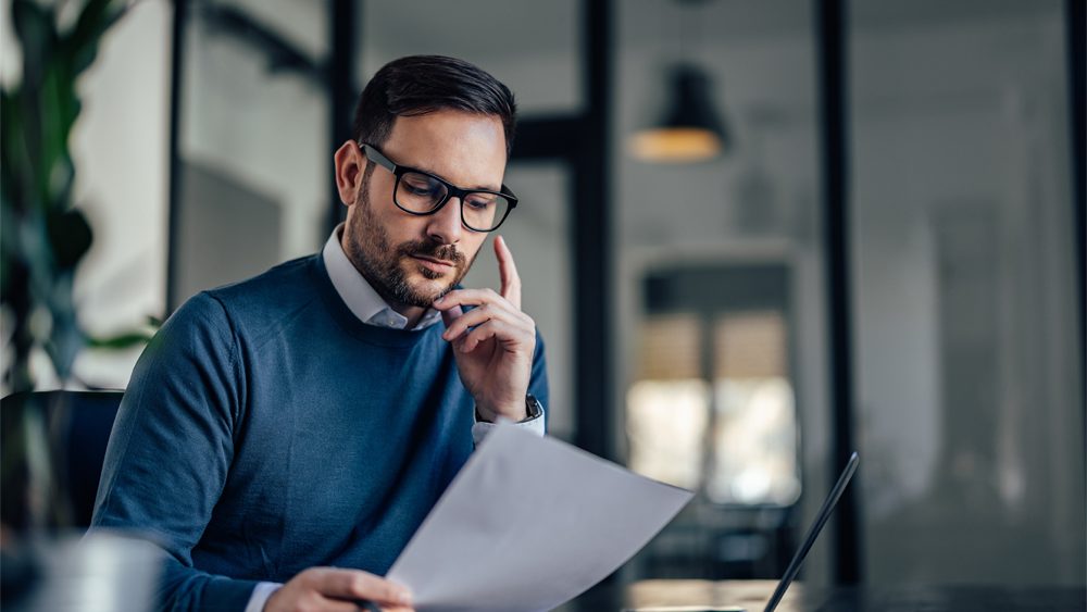 Portrait of a businessman, looking at one document, reading.