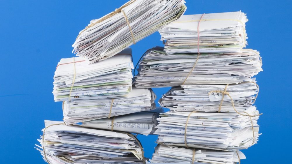 Pile of envelopes, letters, bills, forms. Isolated on blue..
